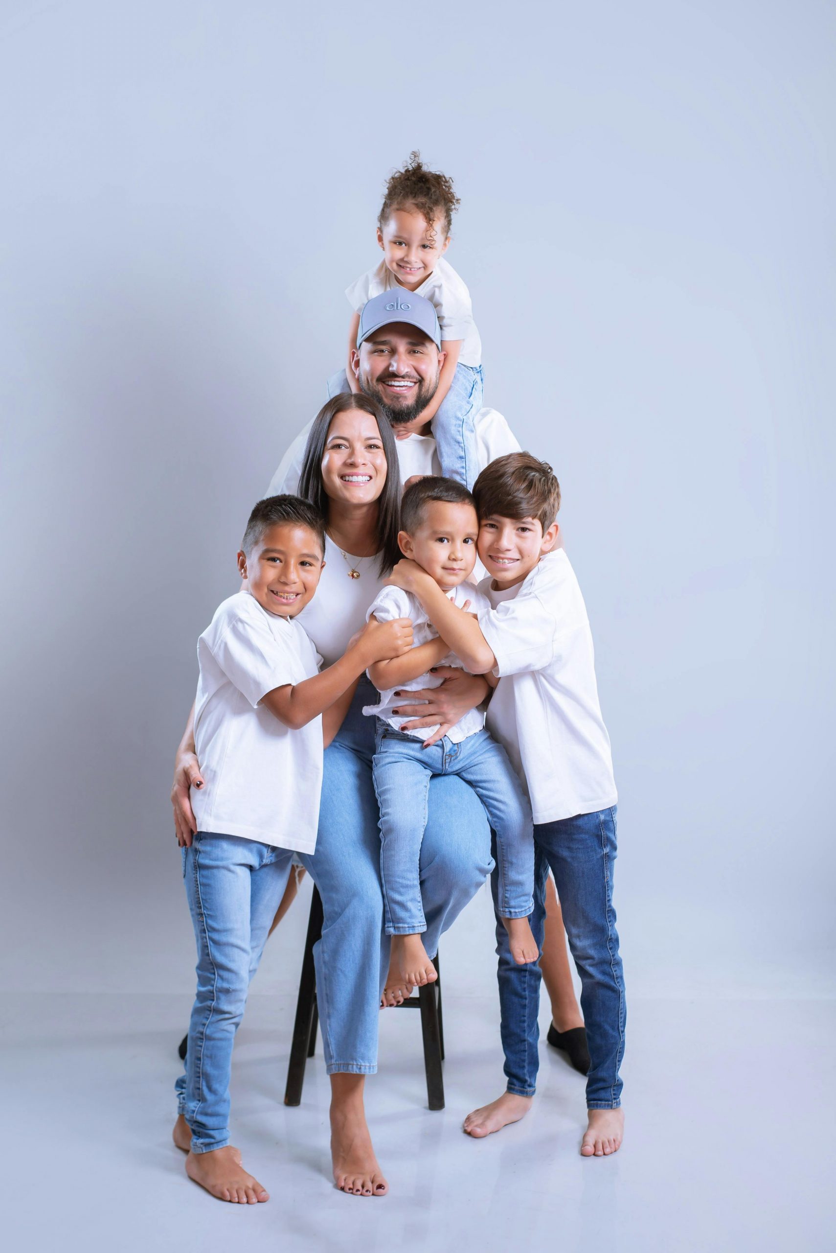 Smiling family of six posing in studio with light background.